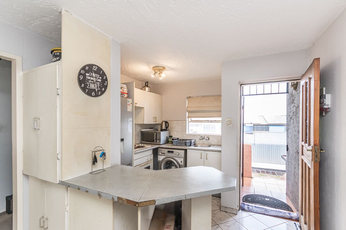 Compact kitchen featuring built-in cabinetry, laminate countertops, and direct access to an outdoor area, offering potential for modernization and improved layout.