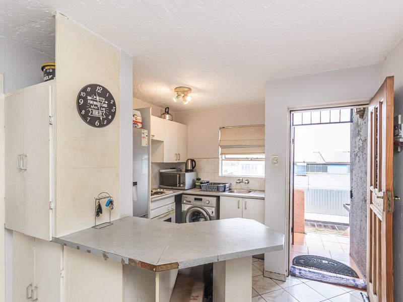 Compact kitchen featuring built-in cabinetry, laminate countertops, and direct access to an outdoor area, offering potential for modernization and improved layout.