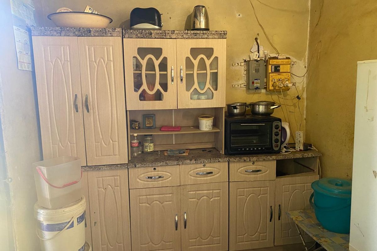 A small kitchen area featuring laminate cabinetry and a granite-look countertop, currently requiring significant wall repairs and electrical maintenance.