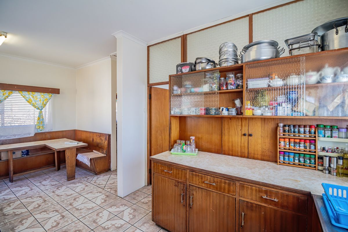 A dated kitchen area featuring built-in wooden cabinetry, laminate countertops, and integrated bench seating with ceramic tile flooring.