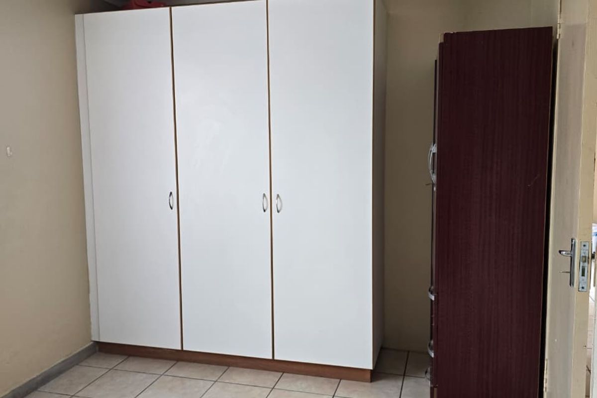A bedroom featuring tiled flooring and built-in white cabinetry, providing functional storage space.