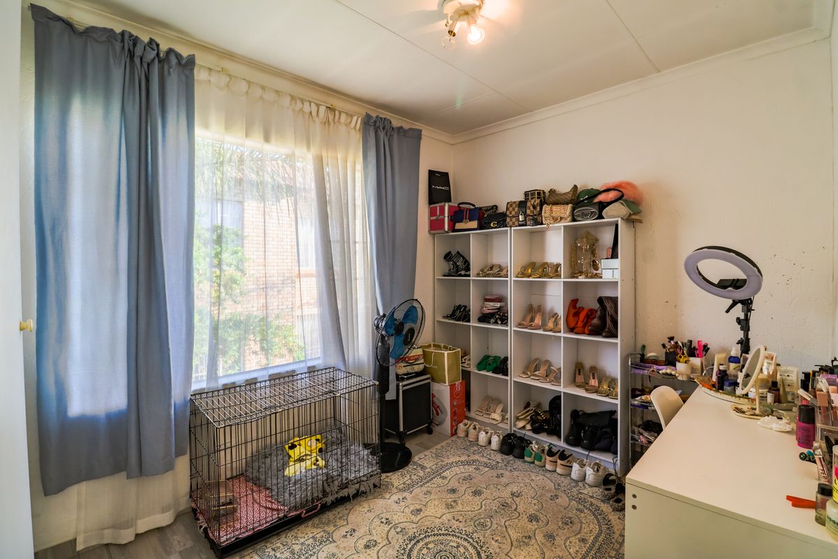 A bedroom featuring a large window with curtains and standard ceiling lighting, offering a functional space for personalization.