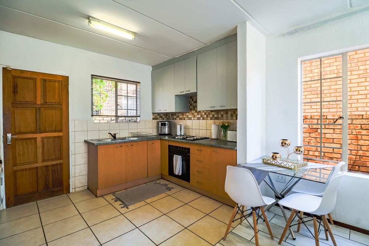 A functional kitchen featuring built-in cabinetry, a gas hob, an integrated oven, and tiled flooring with a neutral backsplash.