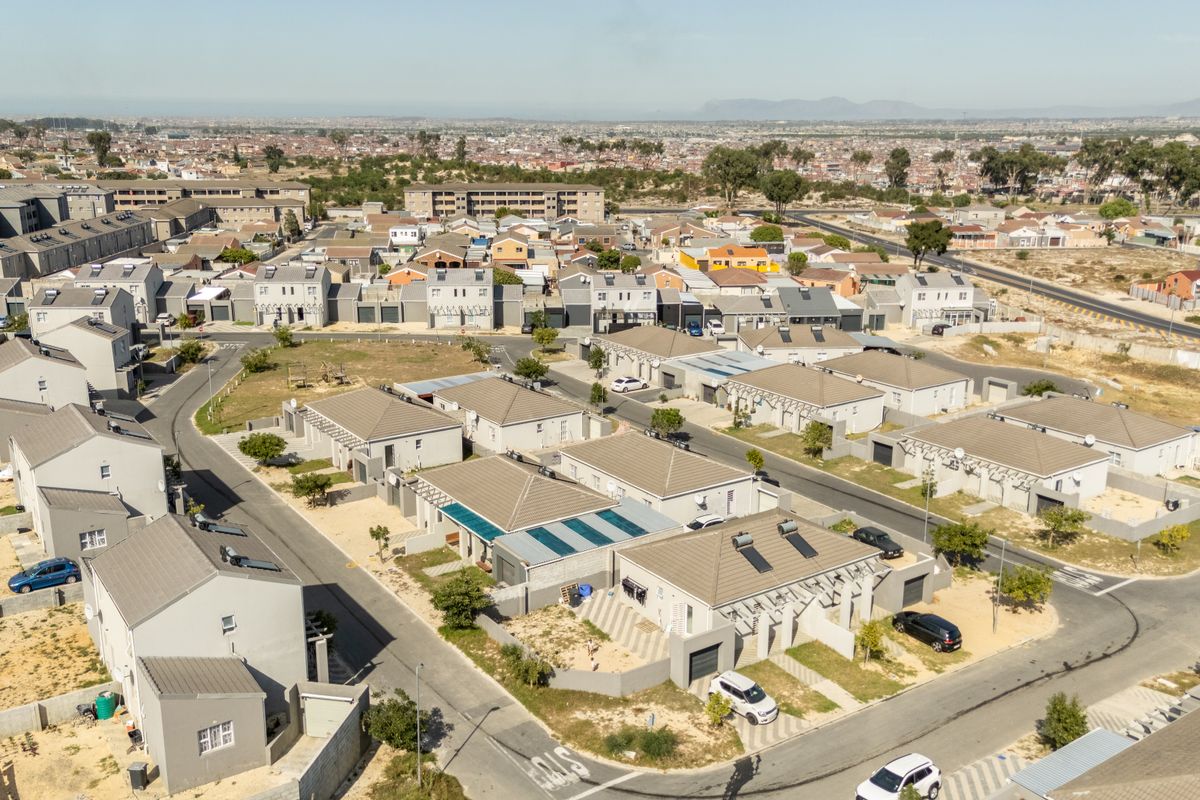 Aerial view of a residential townhouse complex featuring multiple units with tiled roofs, solar water heaters, and paved driveways.
