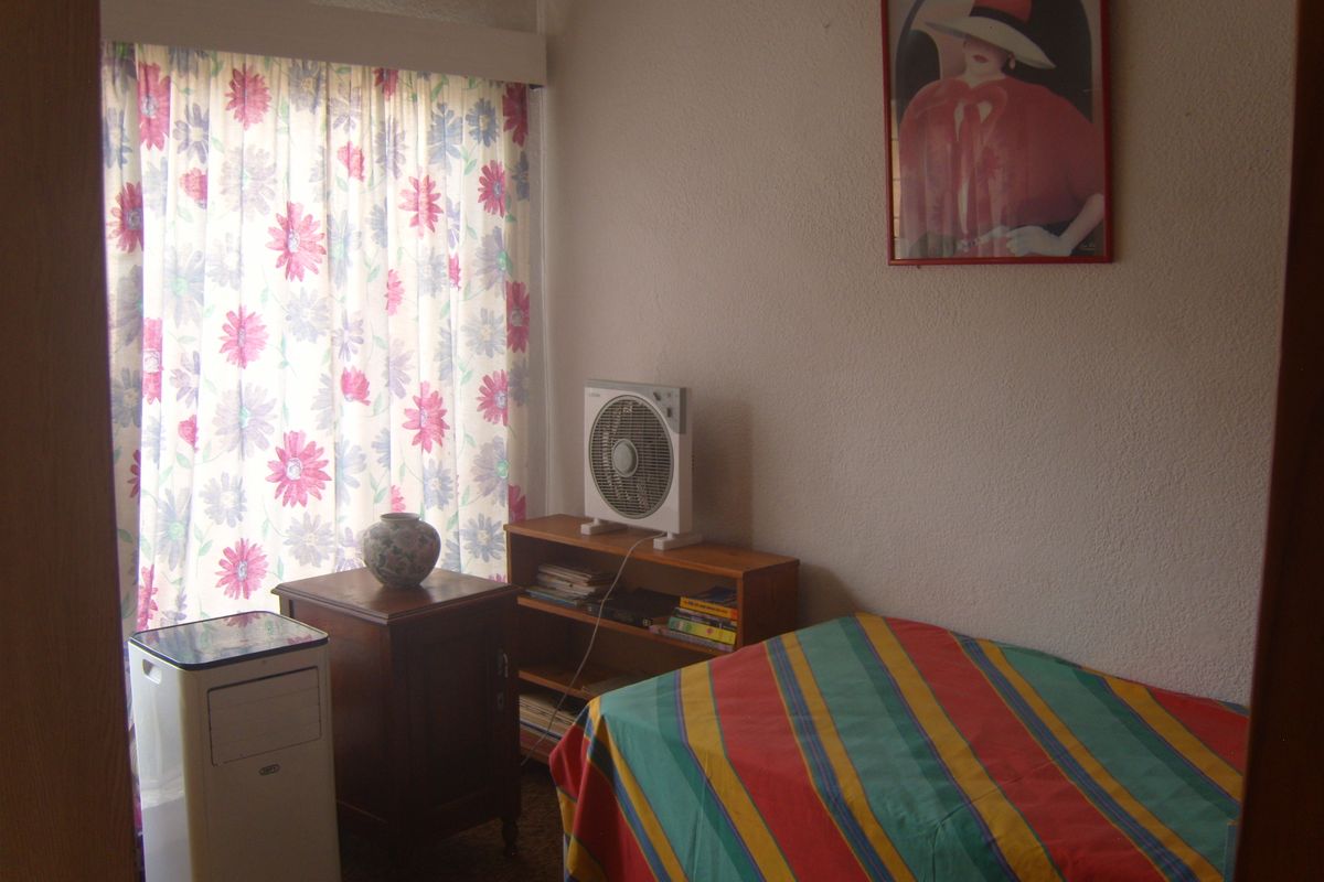 A simple bedroom featuring a window with floral curtains and textured wall finishes.