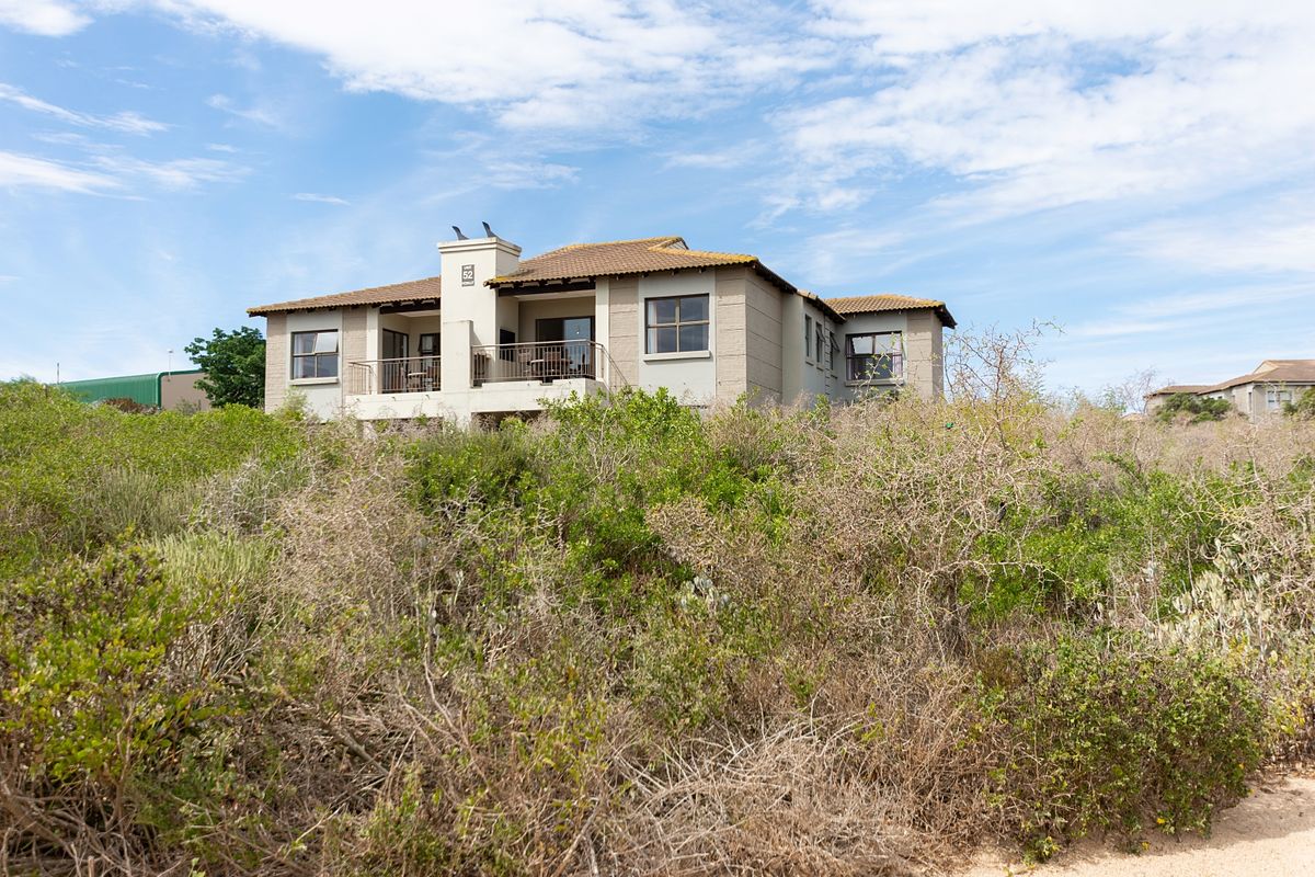 A view of the rear elevation of the apartment building featuring a tiled roof, balcony, and chimney, set against a natural landscape.