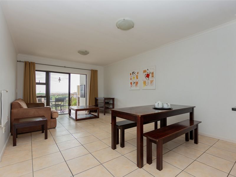 Open plan living and dining area featuring neutral tiled flooring and a large sliding glass door providing access to the balcony.