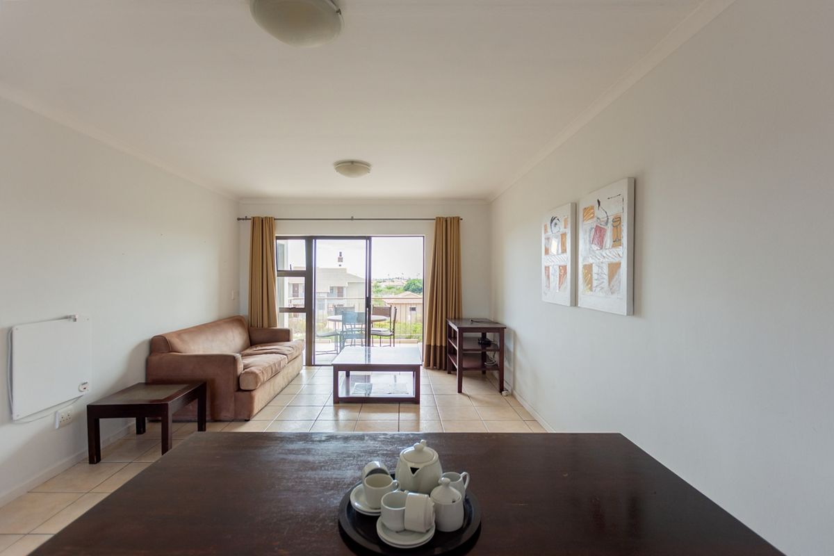 A bright living room featuring tiled flooring and a sliding glass door that opens to an outdoor balcony area.