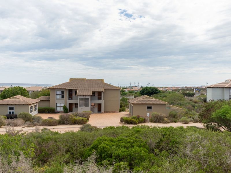 An elevated aerial view of a residential apartment complex featuring tiled roofs, paved driveways, and established surrounding gardens.