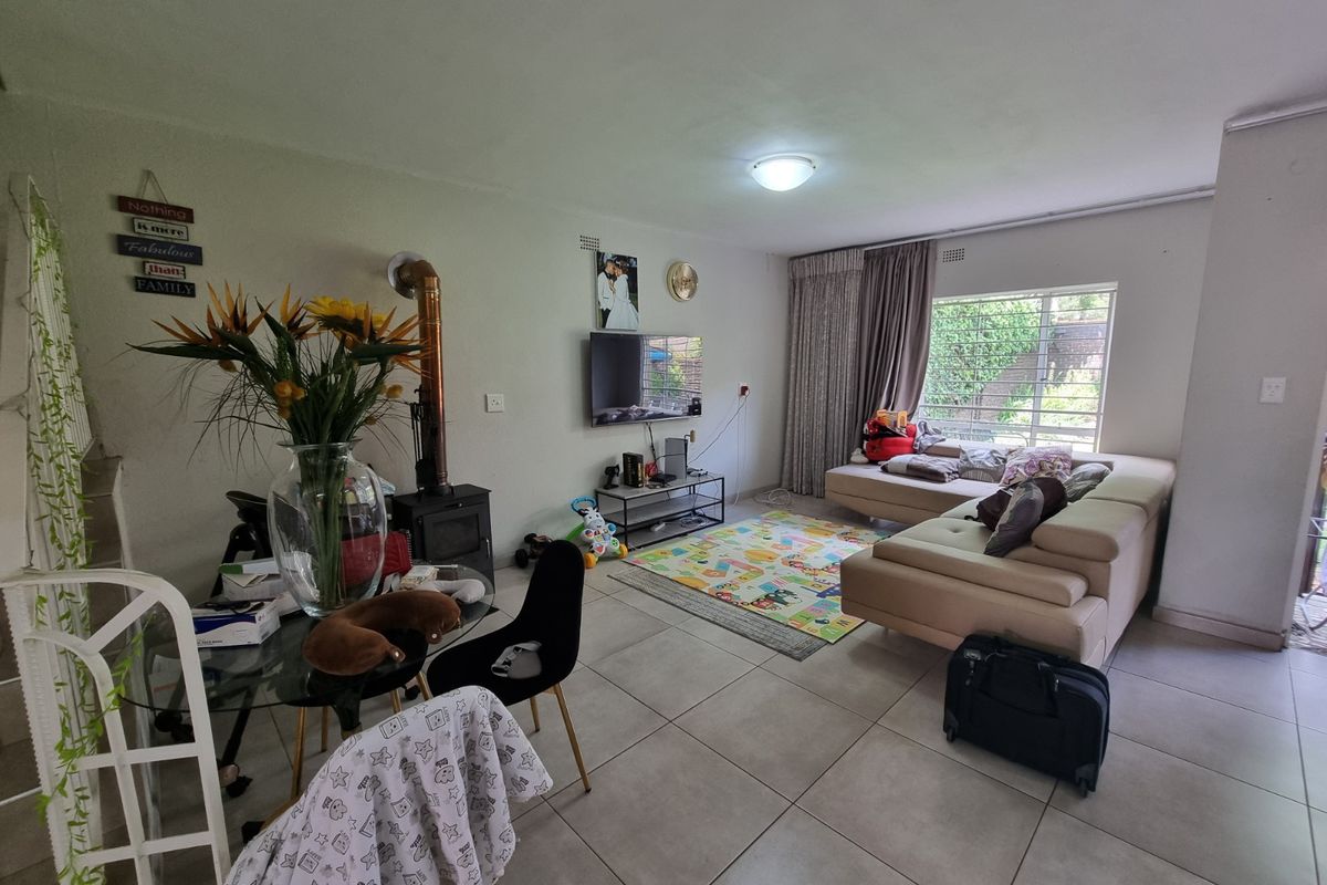 Spacious living room featuring large format floor tiles, a wood-burning fireplace, and natural light through a large window.