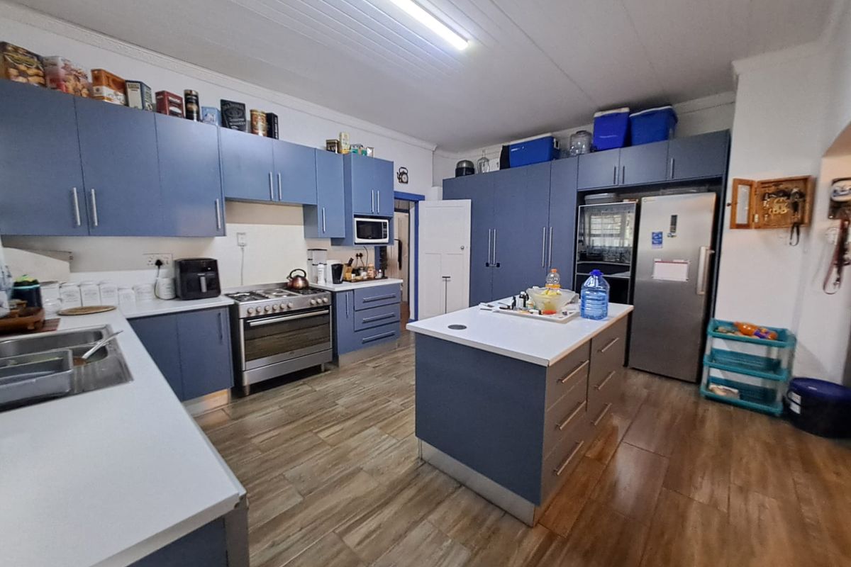 Spacious kitchen featuring blue cabinetry, a central island, stainless steel oven, and wood-look flooring, offering ample storage and workspace.