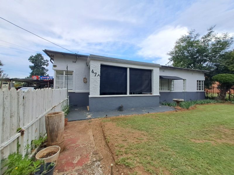 Front view of a single-story house featuring a concrete patio, picket fencing, and established garden area.