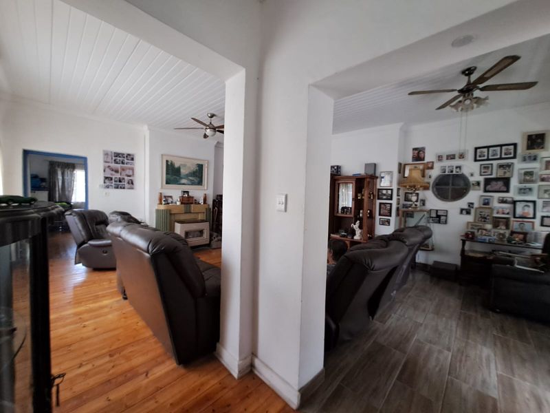 Spacious open-plan living area featuring a mix of hardwood and tiled flooring, timber ceilings, and a built-in fireplace.