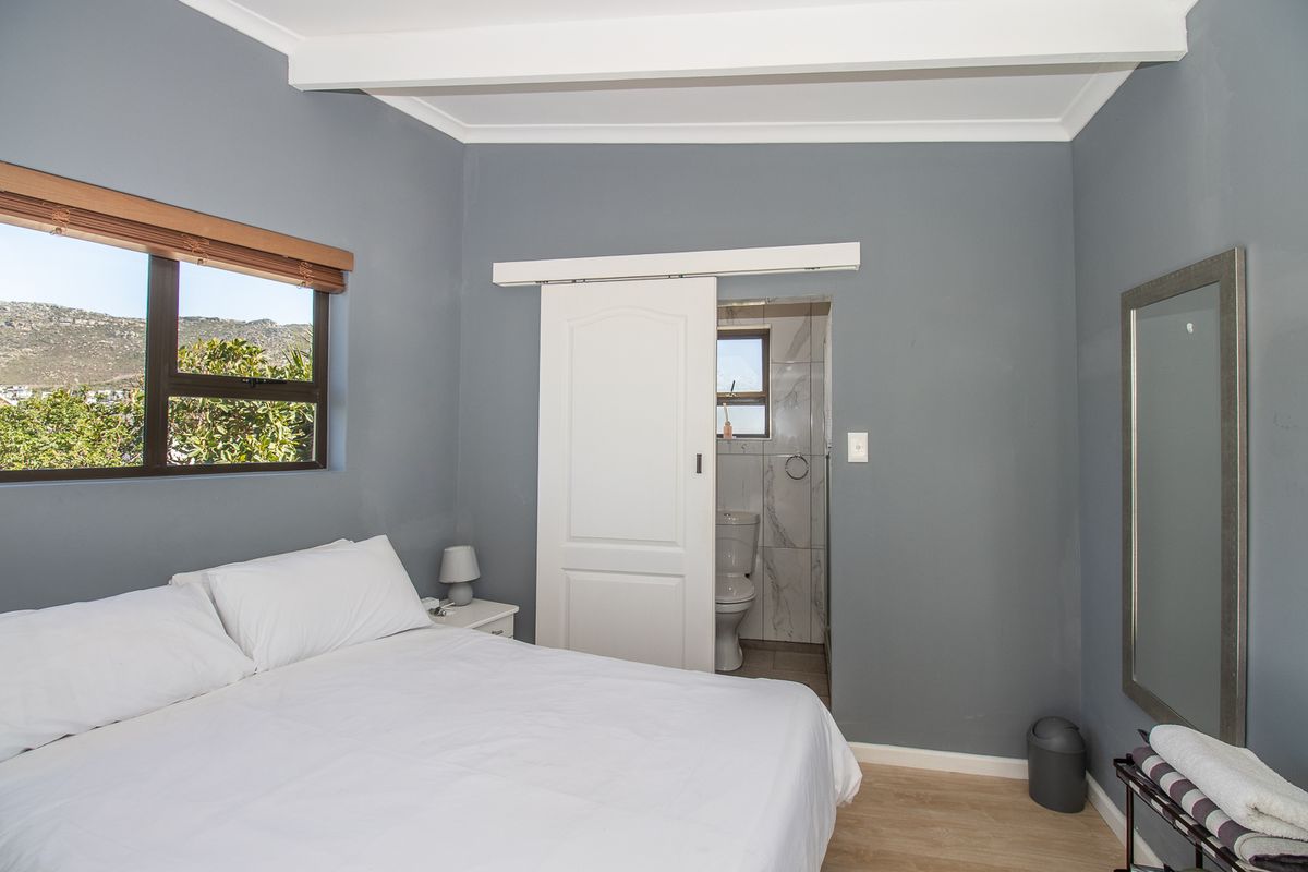 A well-maintained bedroom featuring grey walls, laminate flooring, and an en-suite bathroom accessed via a white sliding door.