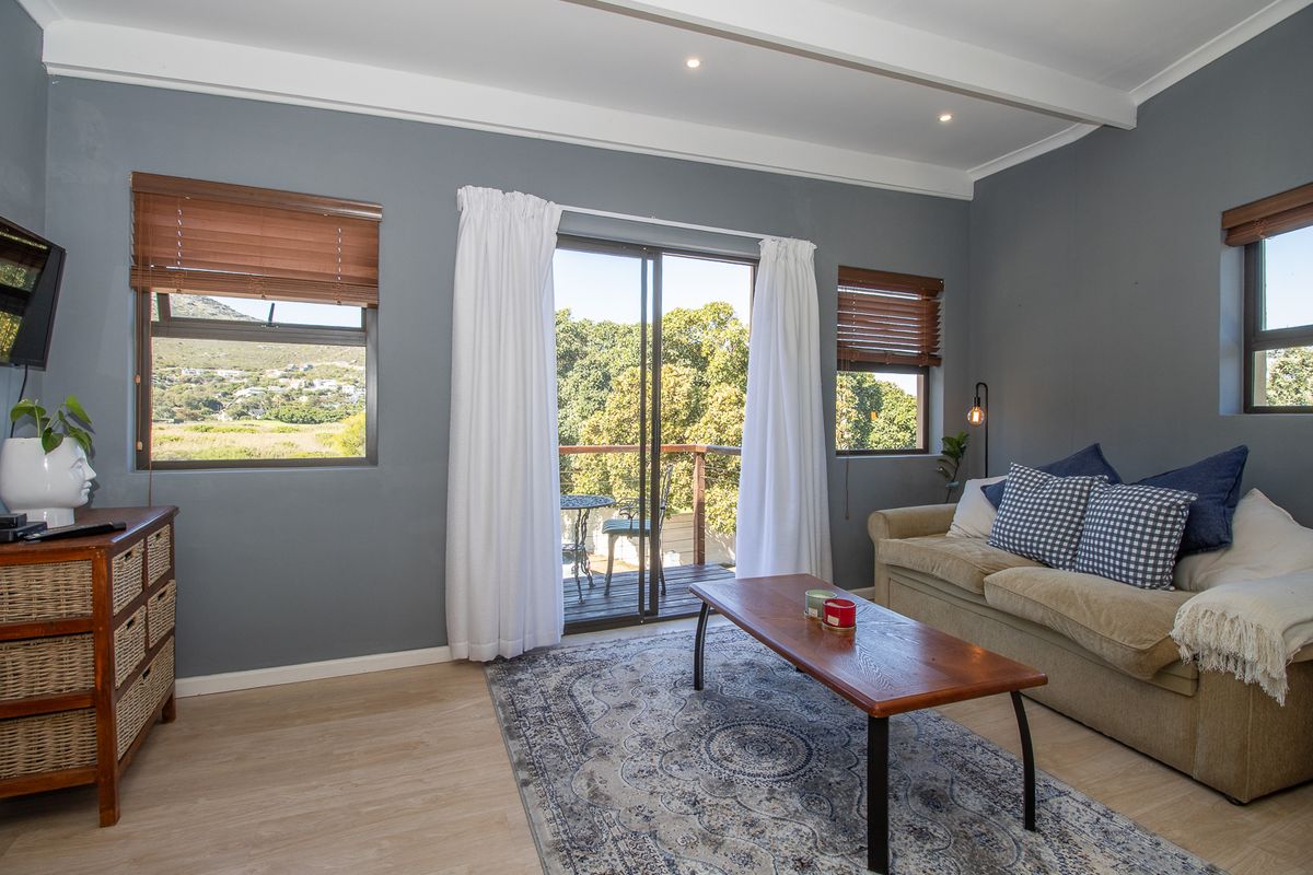 A bright living room featuring laminate flooring, recessed lighting, and sliding glass doors that open onto a private balcony with scenic views.