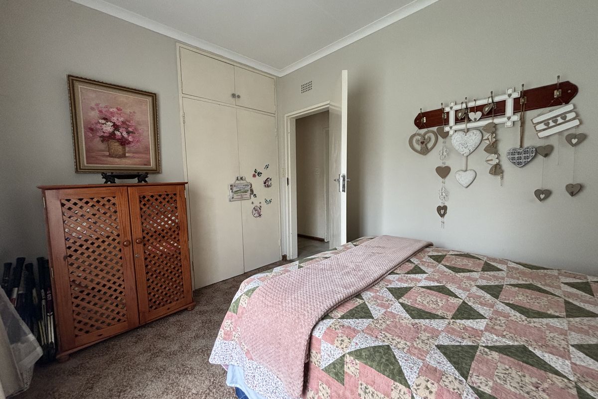 A cozy bedroom featuring built-in cupboards, neutral wall finishes, and carpeted flooring, providing a functional and comfortable living space.