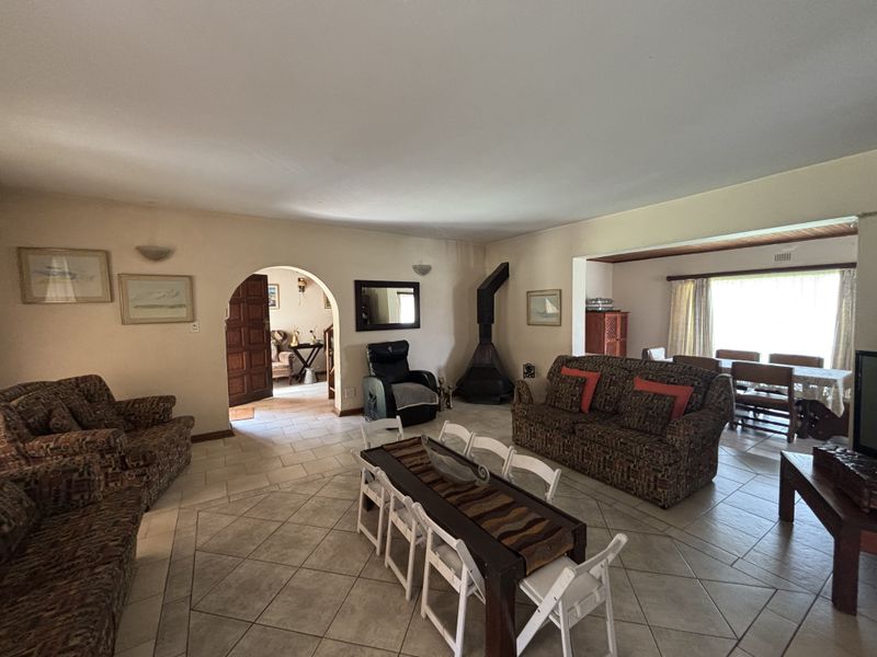 Spacious open-plan living and dining area featuring tiled flooring, a distinctive freestanding fireplace, and an arched entryway leading to adjacent rooms.