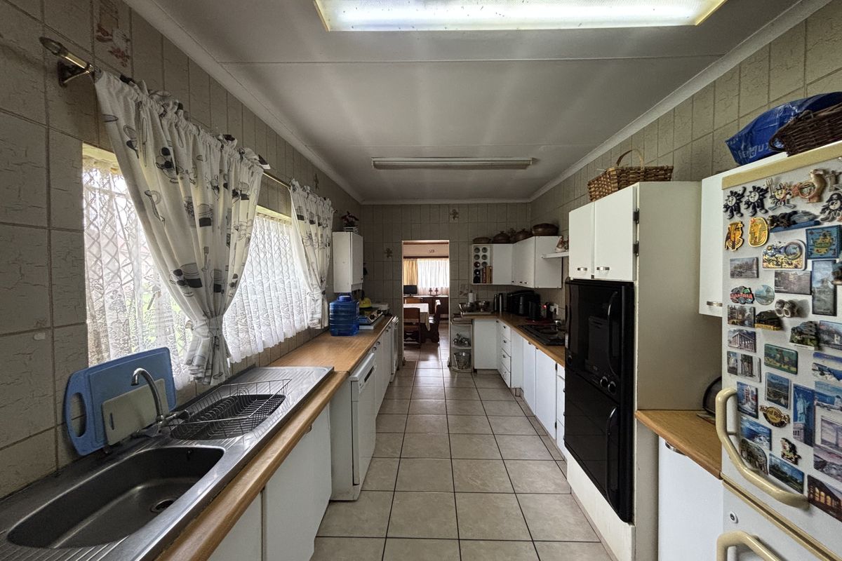 A functional galley-style kitchen featuring tiled walls, ample built-in cabinetry, a double sink, and a built-in oven, offering a classic layout.