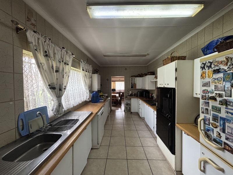 A functional galley-style kitchen featuring tiled walls, ample built-in cabinetry, a double sink, and a built-in oven, offering a classic layout.