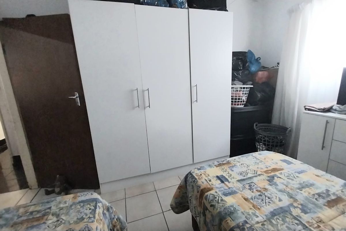 A bedroom featuring tiled flooring and a large white built-in wardrobe.