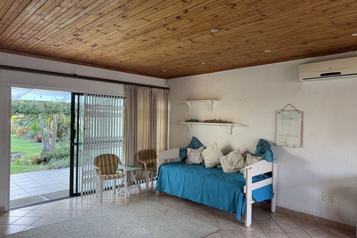 Living area featuring a timber ceiling, tiled floors, split system air conditioning, and direct access to the outdoor patio through a sliding glass door.