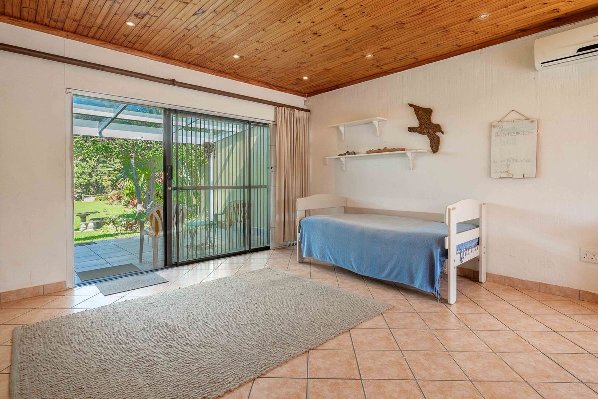 A bedroom featuring timber ceilings, tiled flooring, and a sliding glass door providing direct access to the outdoor patio area.