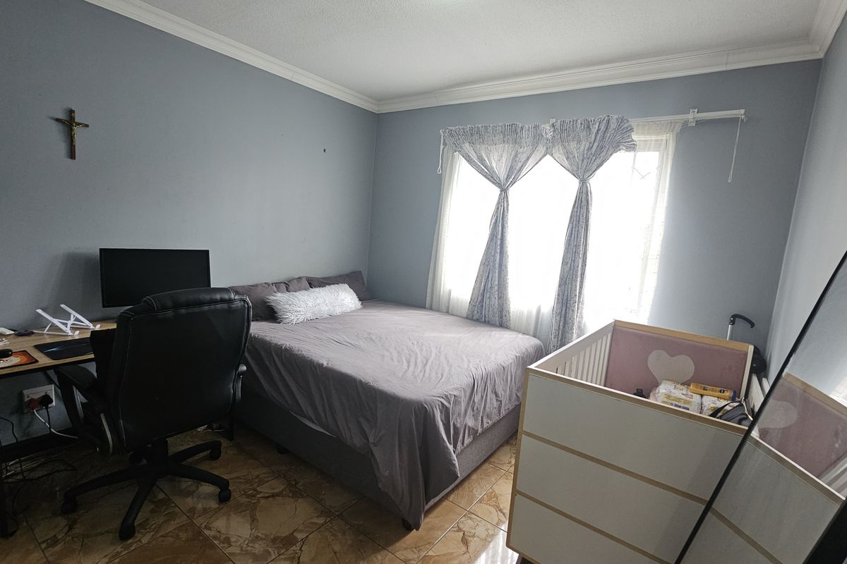 A functional bedroom featuring tiled flooring and crown molding, offering a neutral base for personalization.