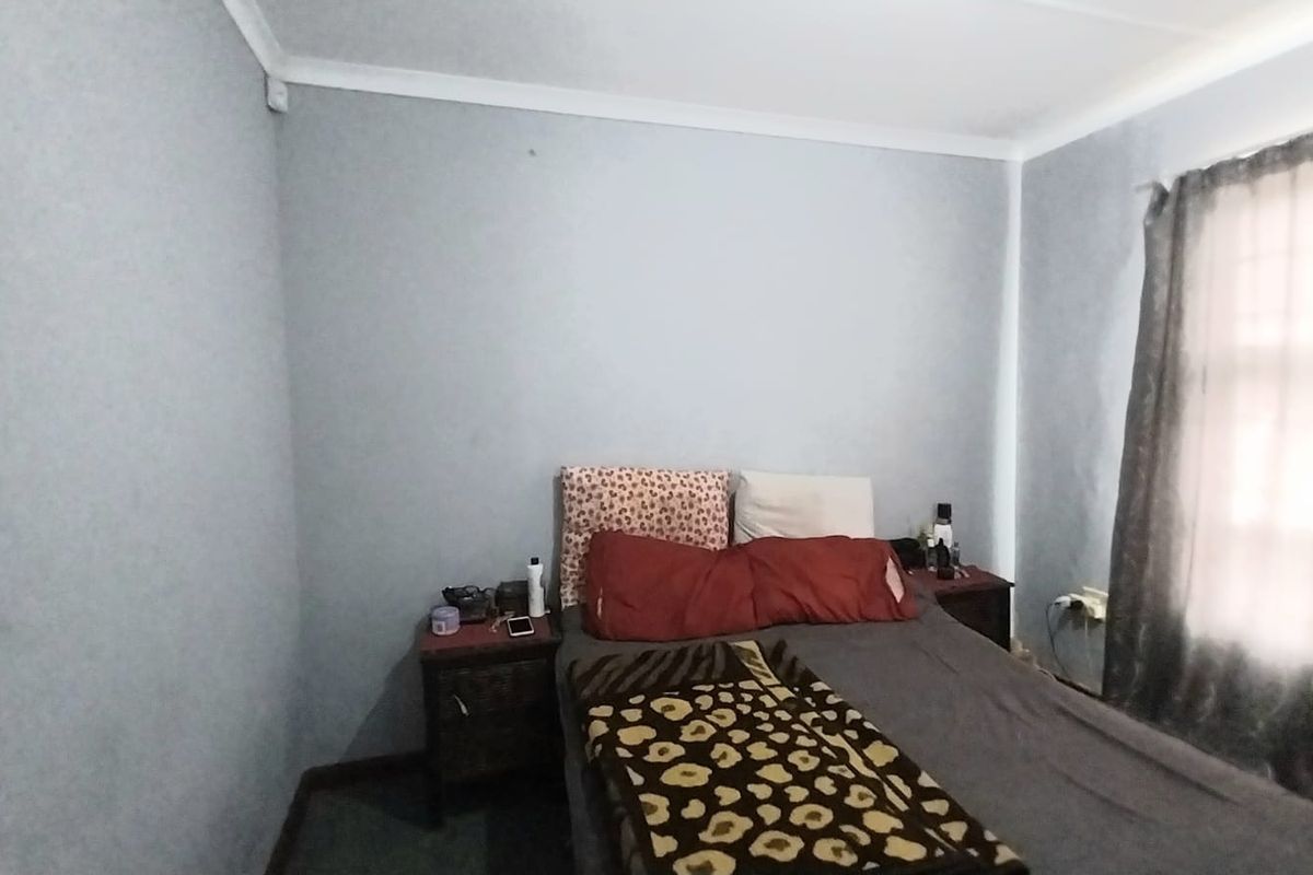A standard bedroom featuring neutral wall finishes and a window with curtains, providing a functional space for rest.