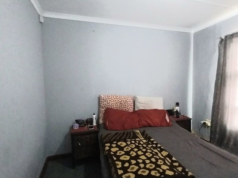 A standard bedroom featuring neutral wall finishes and a window with curtains, providing a functional space for rest.