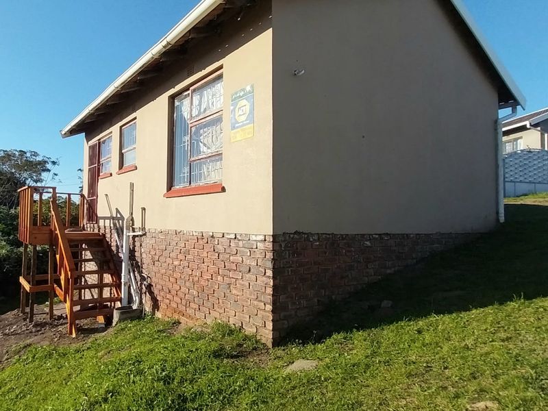 Rear view of the property featuring a brick plinth foundation, timber staircase access, and security bars on the windows.