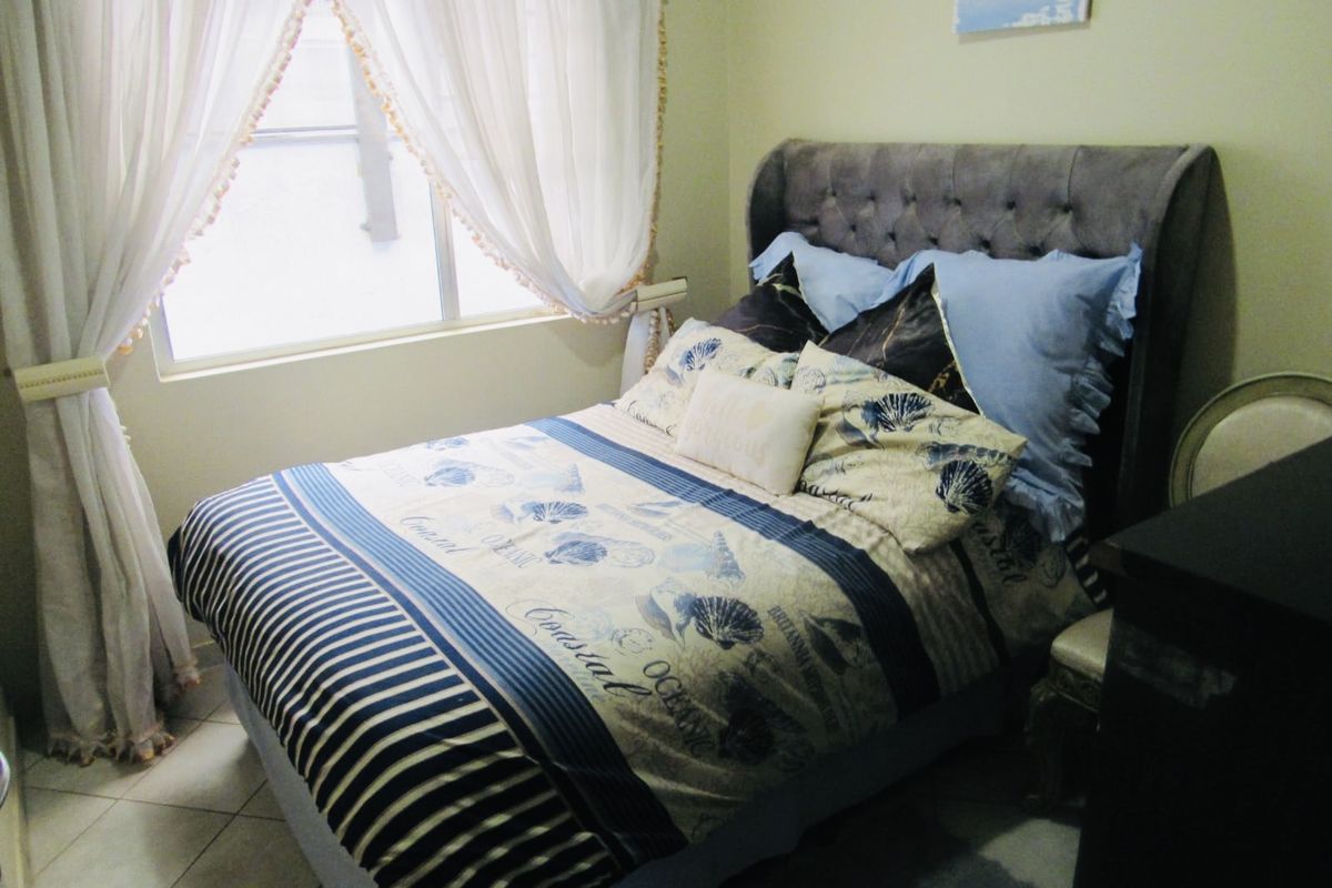A cozy bedroom featuring tiled flooring and a window with natural light, providing a comfortable and functional sleeping space.