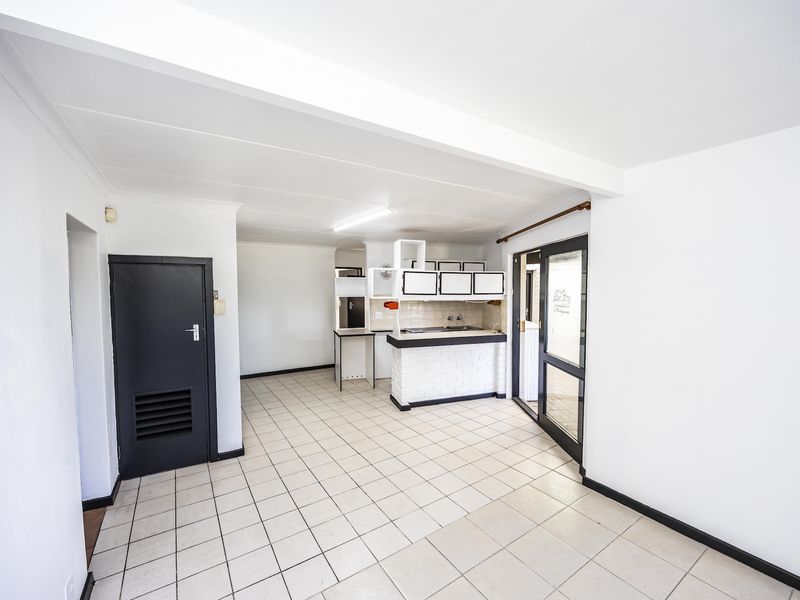 An open-plan living and kitchen area featuring tiled flooring, a brick-base kitchen counter, and a glass sliding door leading to the exterior.