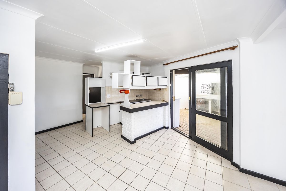 An empty kitchen area featuring tiled flooring, a breakfast bar, and a sliding glass door providing access to the exterior.