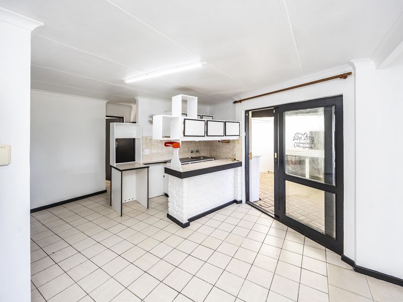 An empty kitchen area featuring tiled flooring, a breakfast bar, and a sliding glass door providing access to the exterior.