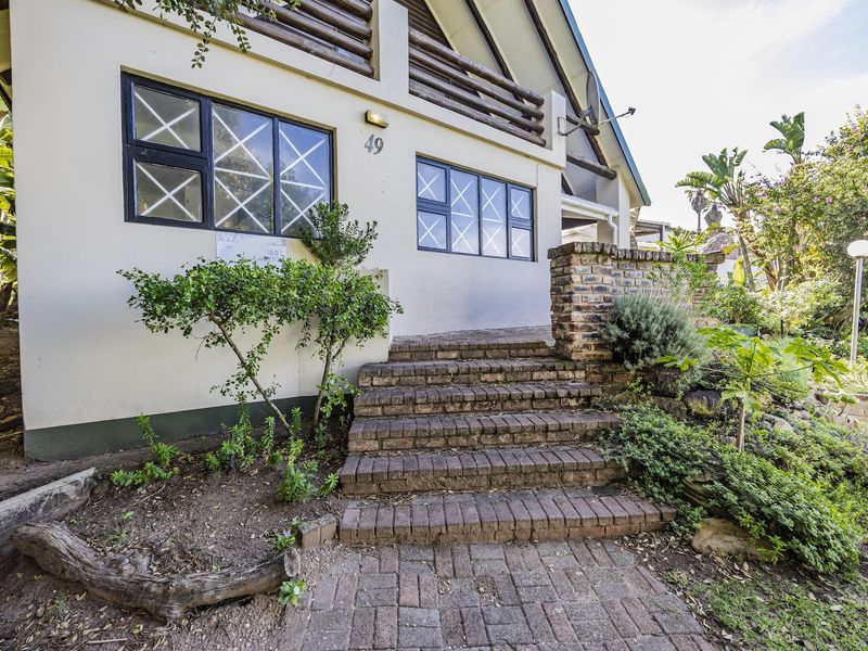 Front entrance of the house featuring a brick staircase, paved walkway, and established garden landscaping.