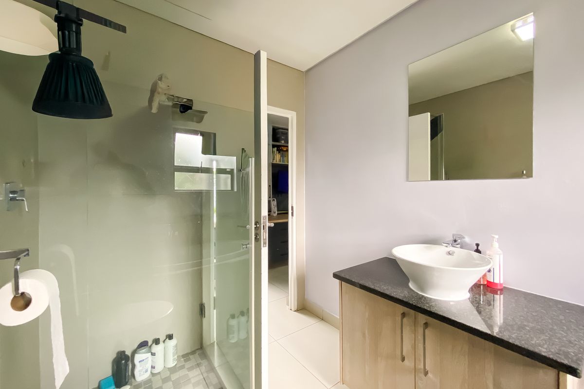 A modern bathroom featuring a glass-enclosed shower, a vanity with a granite countertop and vessel sink, and neutral wall finishes.