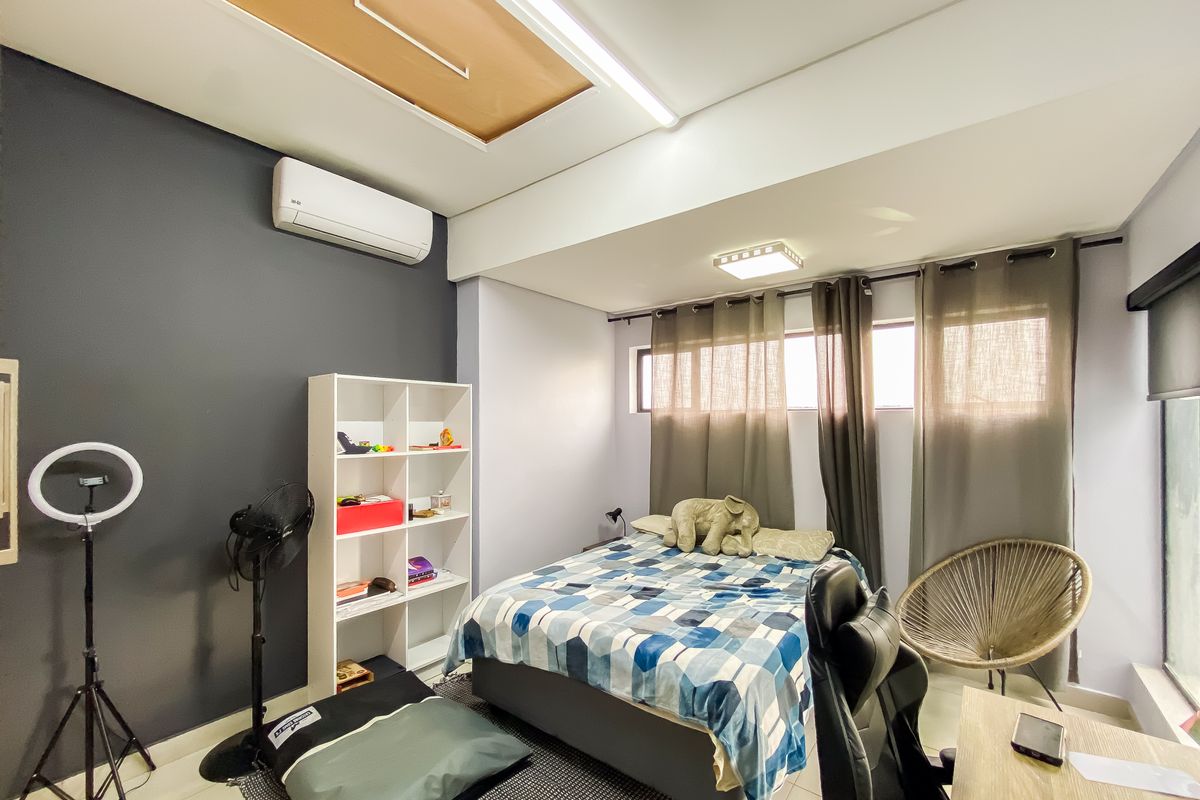 A functional bedroom featuring a split-system air conditioner, neutral wall finishes, and a ceiling access hatch.