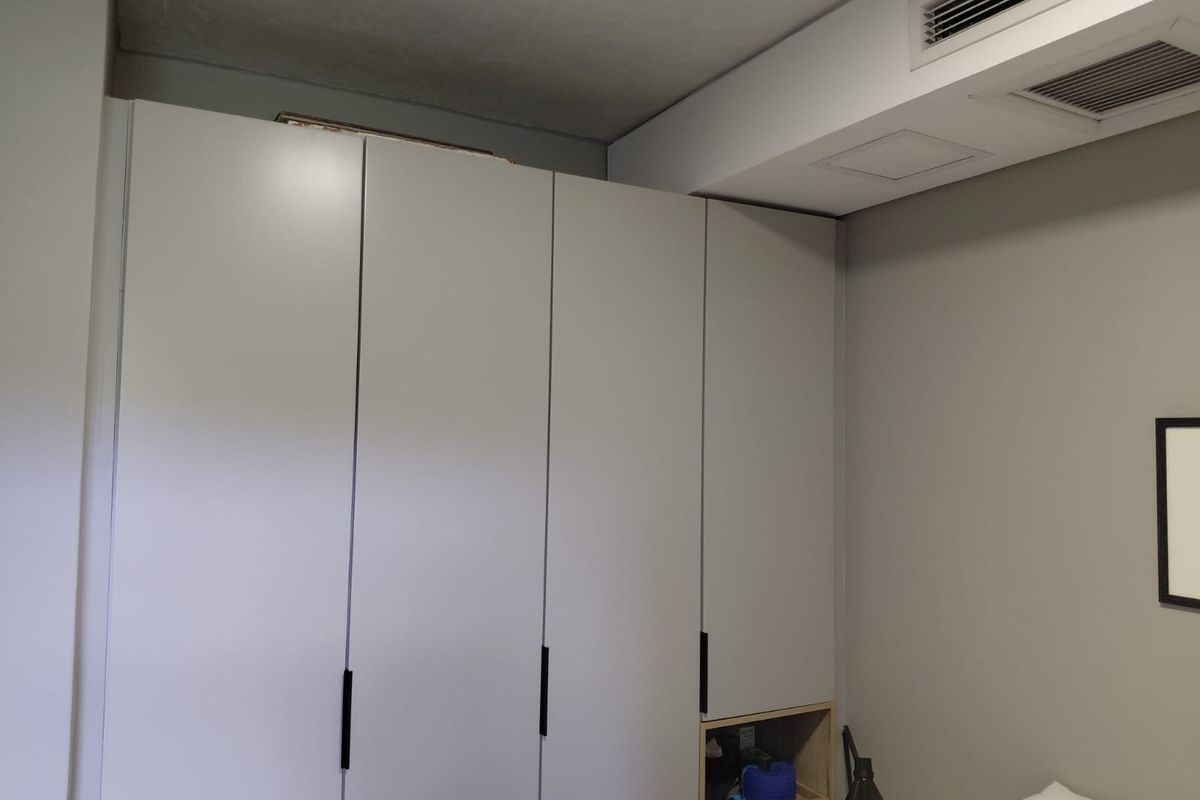 A bedroom featuring a modern built-in wardrobe with integrated shelving and ducted air conditioning ventilation.