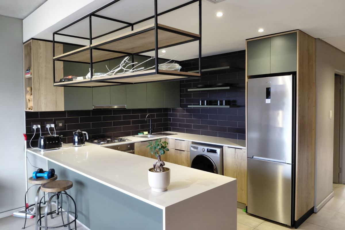 Modern kitchen featuring quartz countertops, a gas hob, integrated appliances, and a stylish suspended metal shelving unit above the breakfast bar.