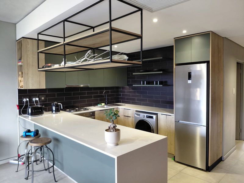 Modern kitchen featuring quartz countertops, a gas hob, integrated appliances, and a stylish suspended metal shelving unit above the breakfast bar.