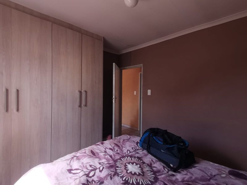 A bedroom featuring built-in wooden cupboards and dark-toned walls, providing a functional storage solution within the sleeping area.