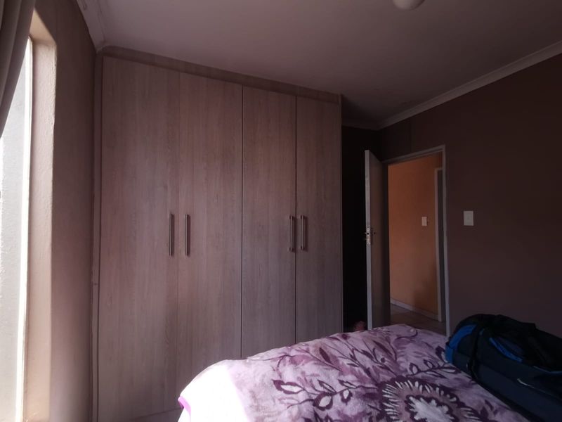 A bedroom featuring built-in wooden cupboards and neutral wall finishes.