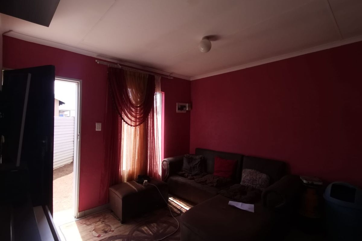 A living room area featuring dark red walls, coving, and an internal electrical distribution board, with direct access to an outdoor space.