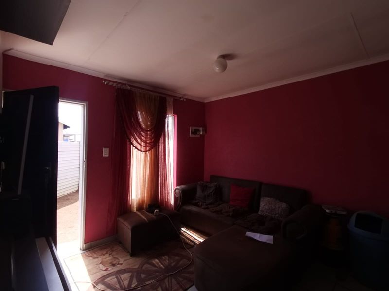 A living room area featuring dark red walls, coving, and an internal electrical distribution board, with direct access to an outdoor space.