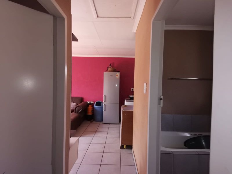 A view from a hallway looking into an open plan living and kitchen area, with a bathroom visible to the right.