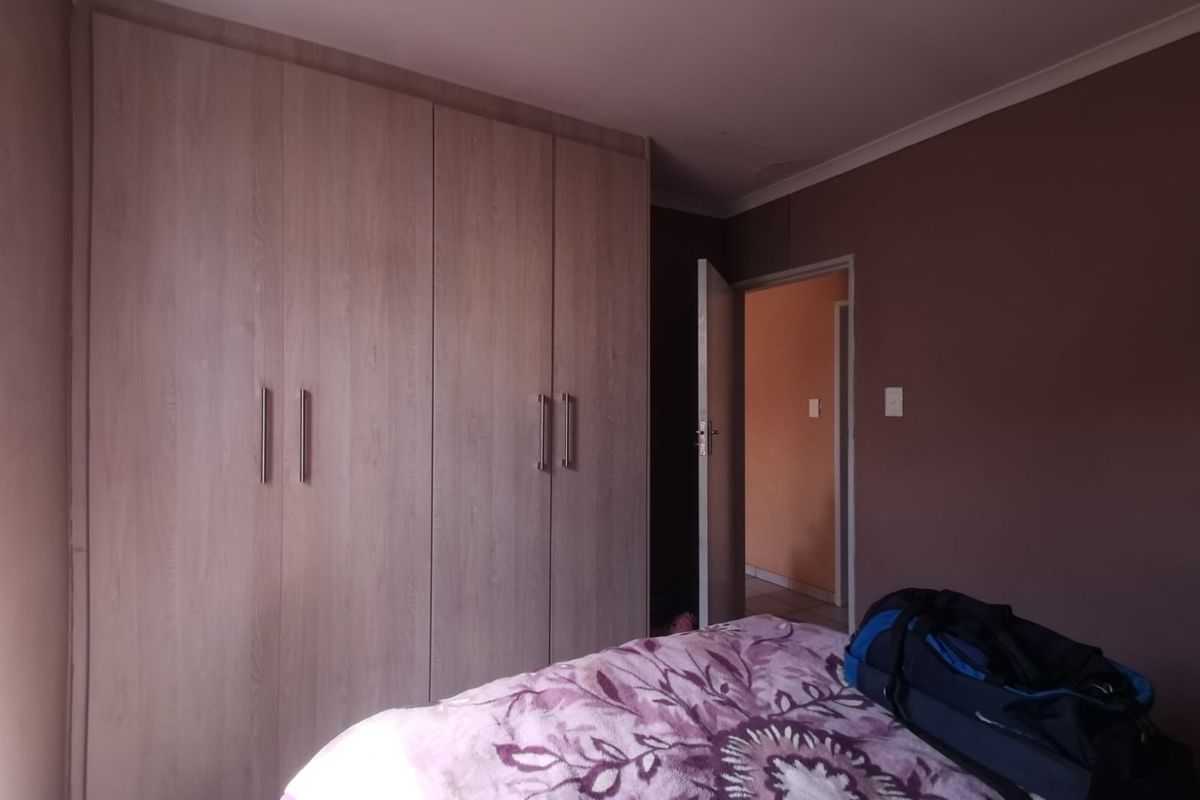 A bedroom featuring built-in wooden cupboards and coved ceiling detailing, providing functional storage space.