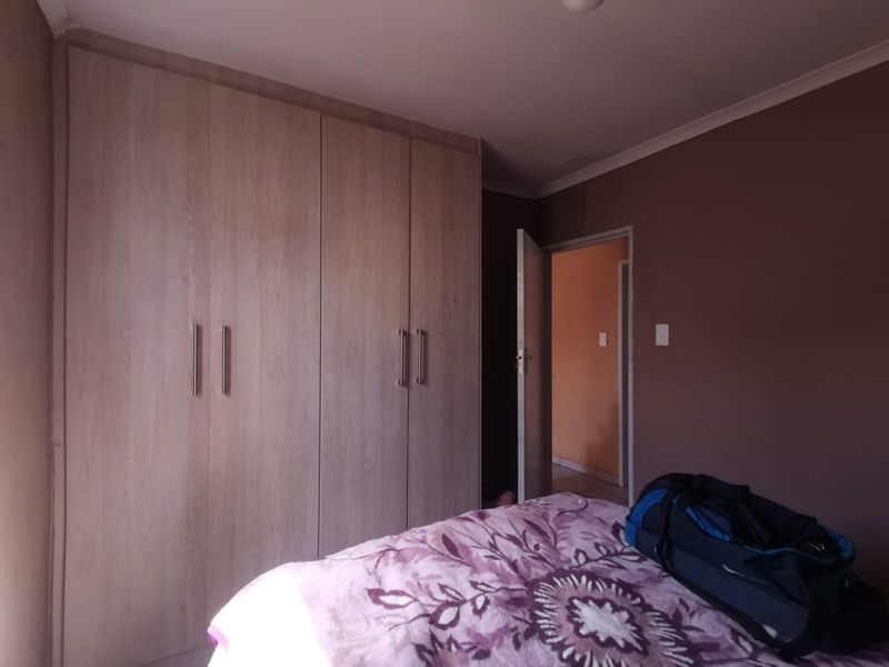 A bedroom featuring built-in wooden cupboards and coved ceiling detailing, providing functional storage space.