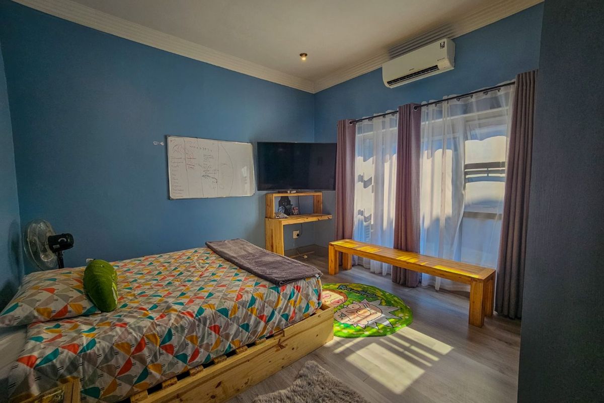 A bedroom featuring light wood-look flooring, blue painted walls, recessed ceiling lighting, and a wall-mounted air conditioning unit.