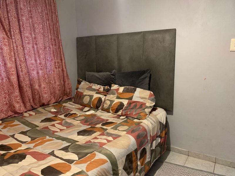 A bedroom featuring tiled flooring and a neutral wall finish, providing a functional space for rest.