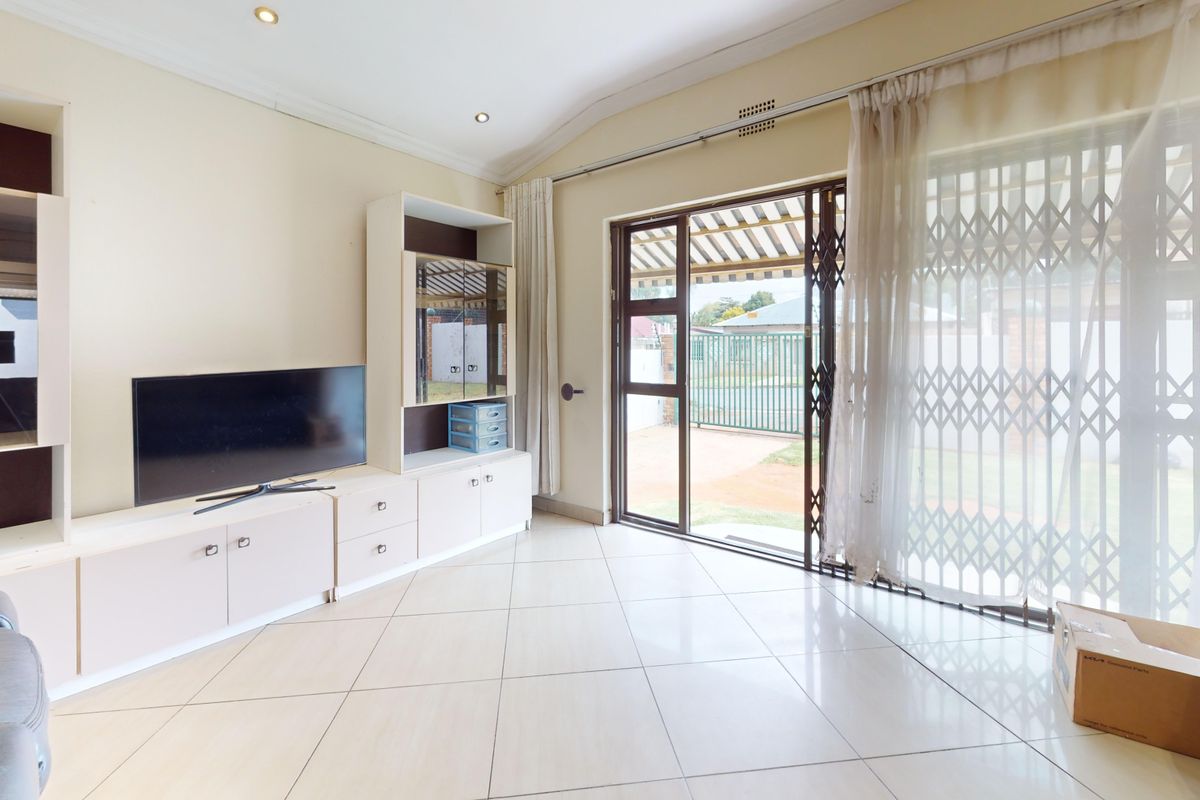 Spacious living room featuring tiled flooring, built-in cabinetry, and a sliding glass door providing direct access to the outdoor area.